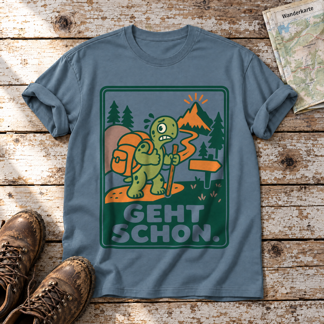 Geht schon – T-Shirt Unisex in Steinblau, flach liegend auf alten Holzbrettern mit Wanderschuhen und Wanderkarte.