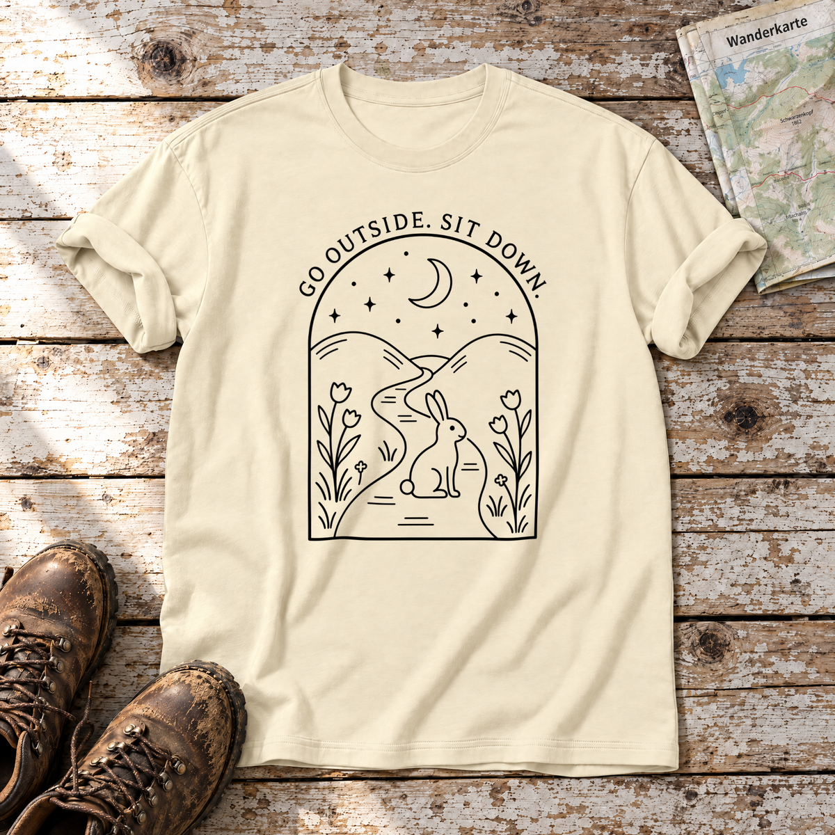 Go outside. Sit down. – T-Shirt Unisex in Natur, flach liegend auf alten Holzbrettern mit Wanderschuhen und Wanderkarte.