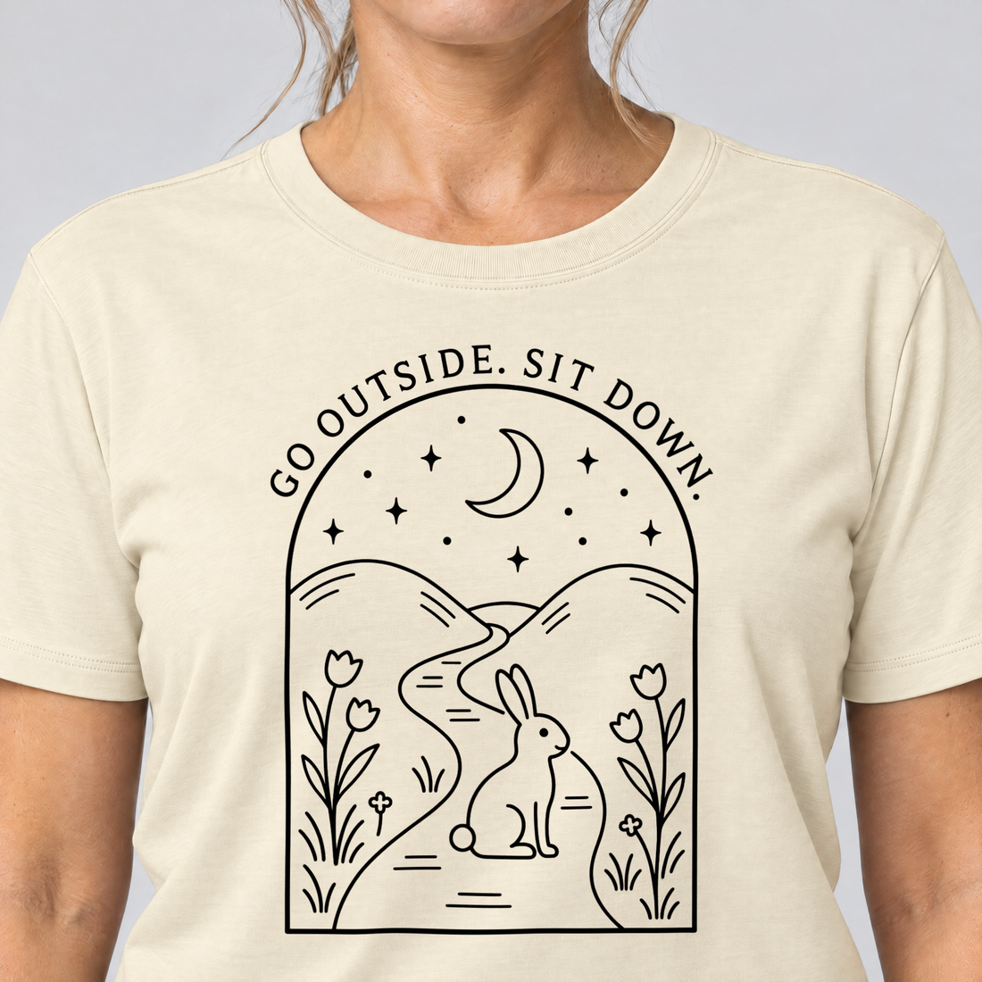 Nahaufnahme des Drucks: Go outside. Sit down. – T-Shirt Unisex in Natur, von einer Frau getragen