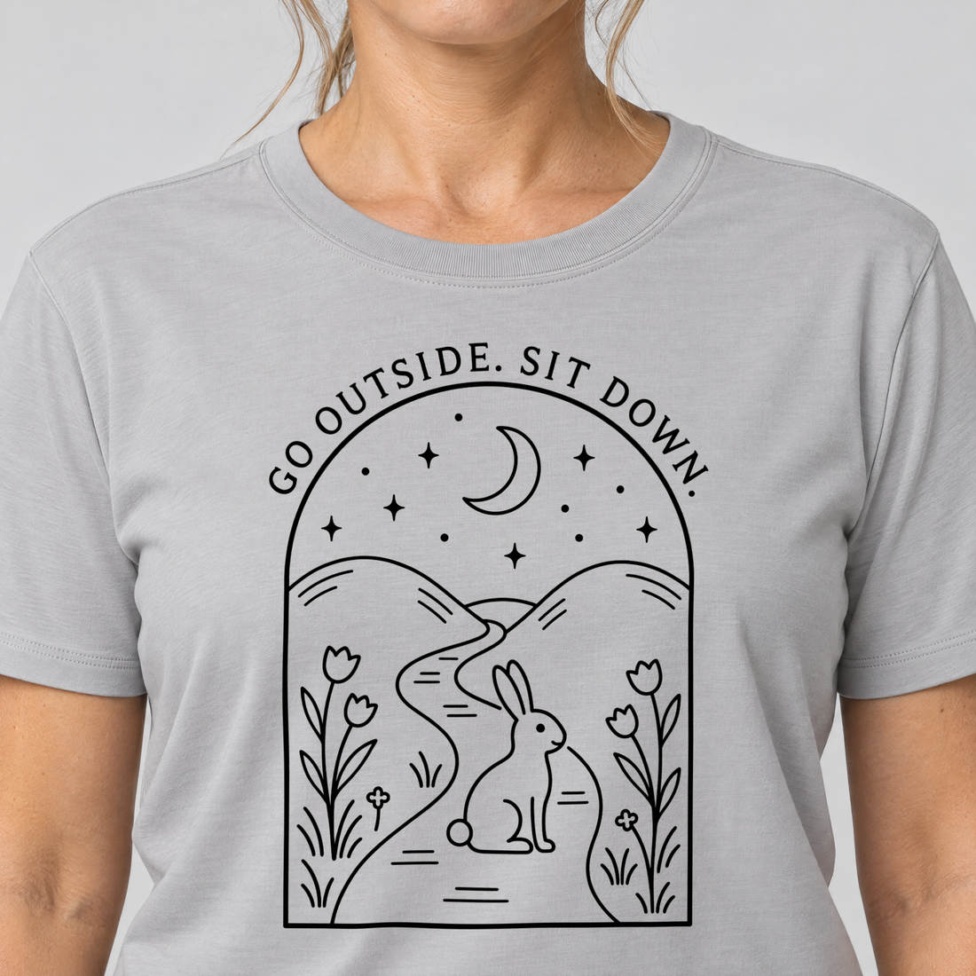 Nahaufnahme des Drucks: Go outside. Sit down. – T-Shirt Unisex in Hellgrau, von einer Frau getragen