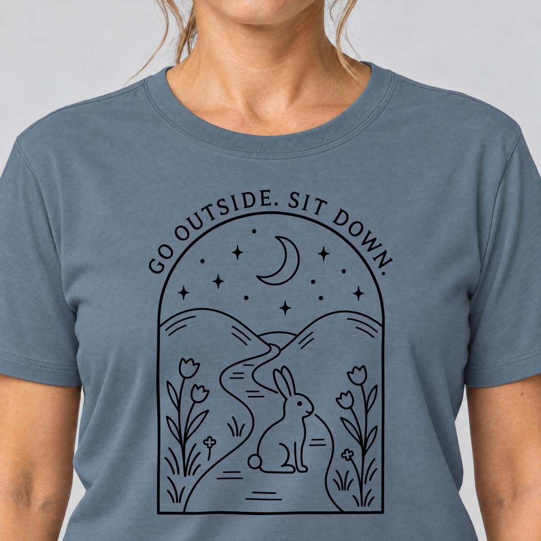 Nahaufnahme des Drucks: Go outside. Sit down. – T-Shirt Unisex in Steinblau, von einer Frau getragen