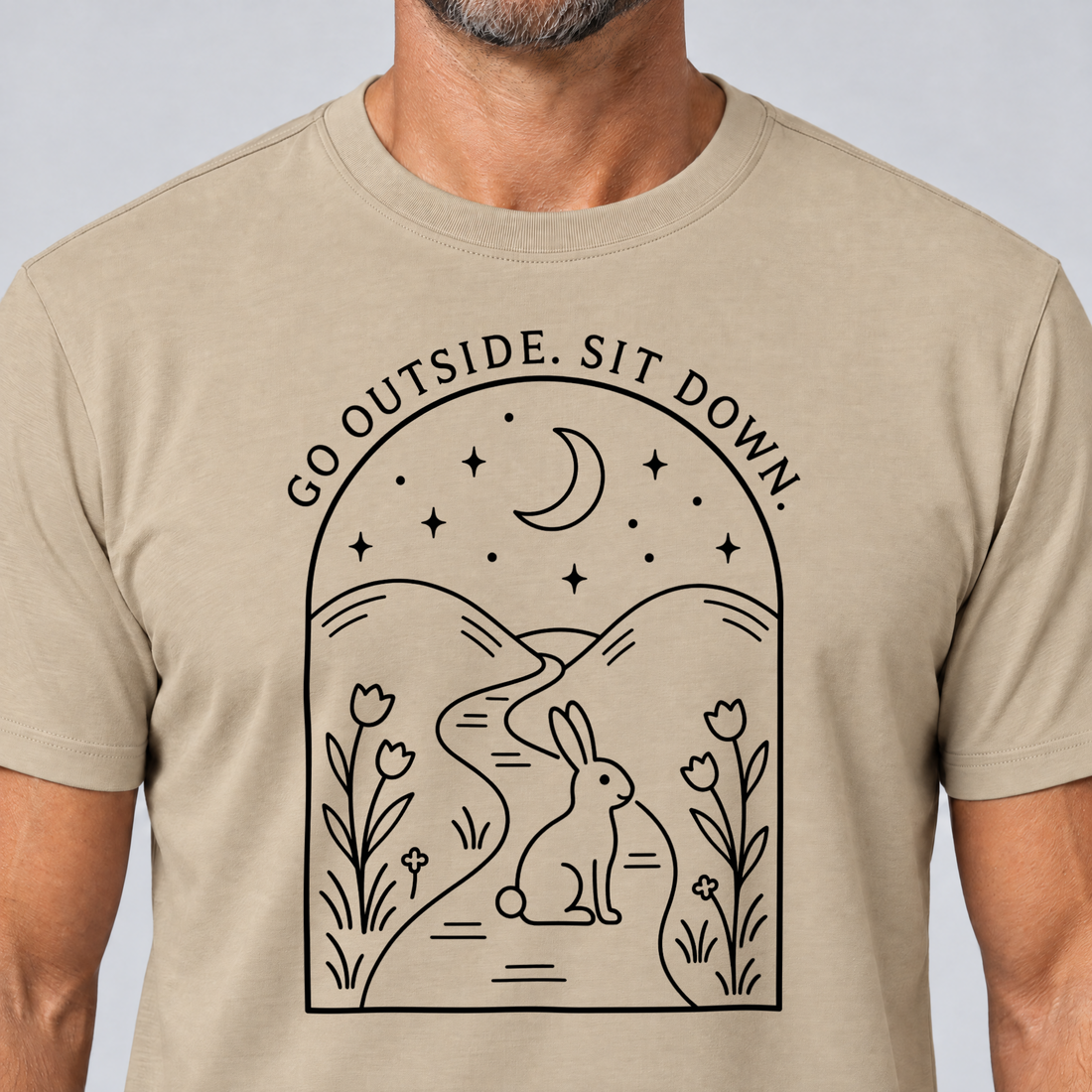 Nahaufnahme des Drucks: Go outside. Sit down. – T-Shirt Unisex in Sand, von einem Mann getragen