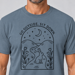 Nahaufnahme des Drucks: Go outside. Sit down. – T-Shirt Unisex in Steinblau, von einem Mann getragen