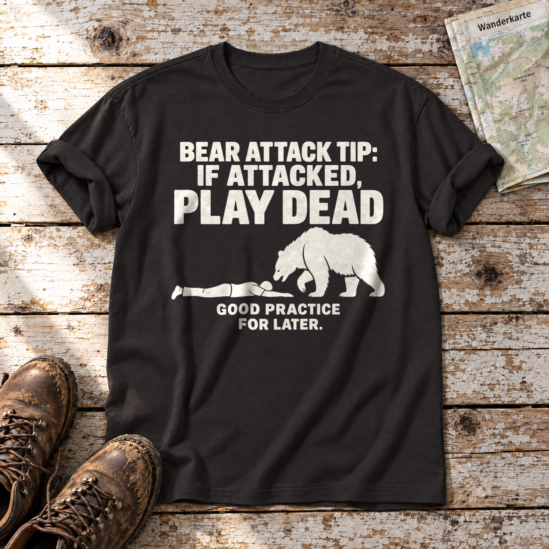 Good Practice for Later – T-Shirt Unisex in Schwarz, flach liegend auf alten Holzbrettern mit Wanderschuhen und Wanderkarte.