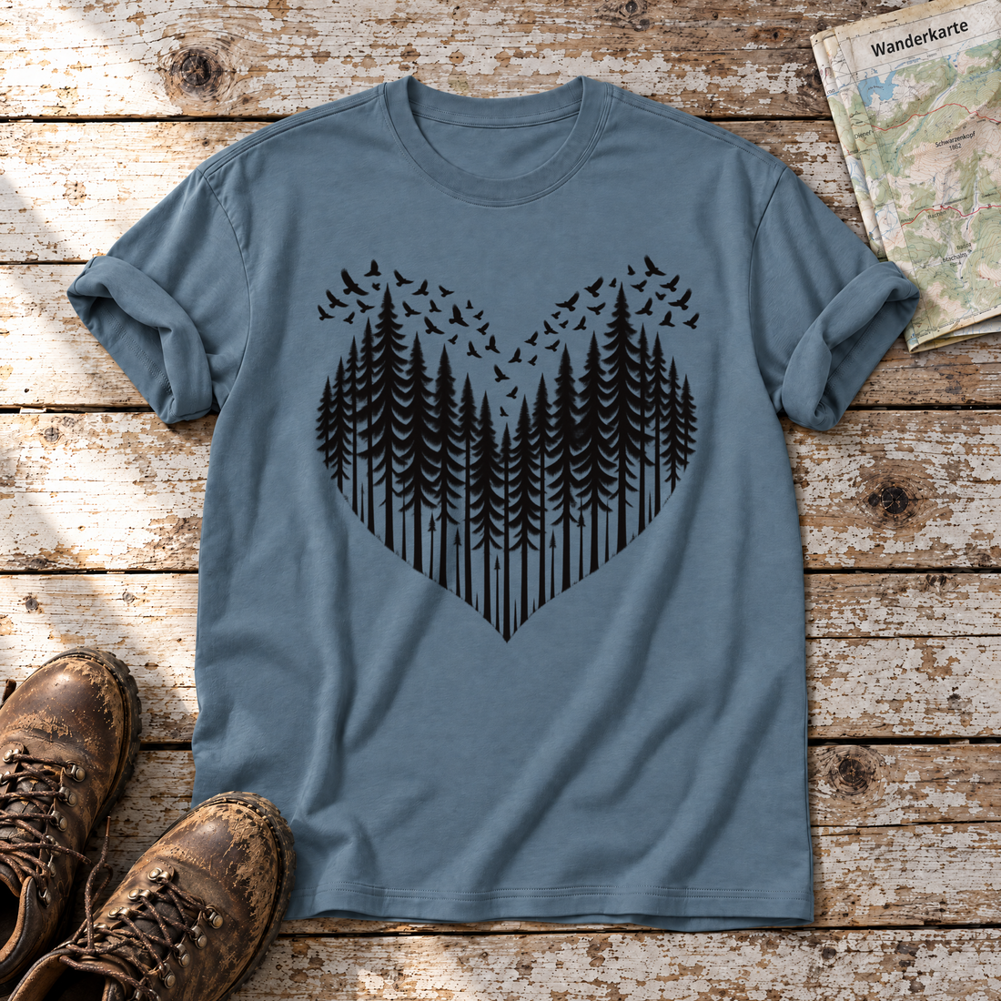 Bergwald-Herz mit Alpendohlen – T-Shirt Unisex in Steinblau, flach liegend auf alten Holzbrettern mit Wanderschuhen und Wanderkarte.