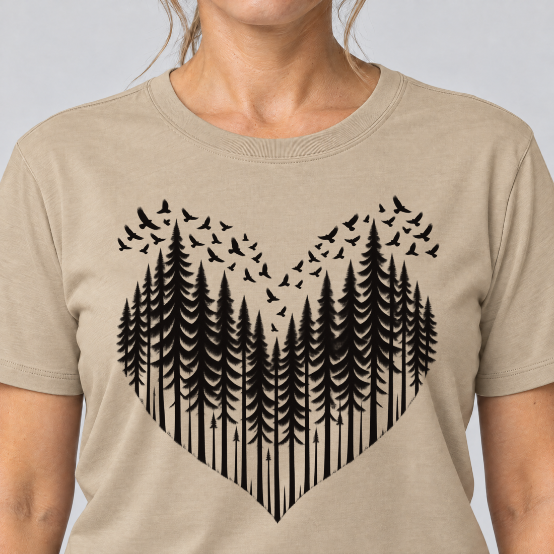 Nahaufnahme des Drucks: Bergwald-Herz mit Alpendohlen – T-Shirt Unisex in Sand, von einer Frau getragen