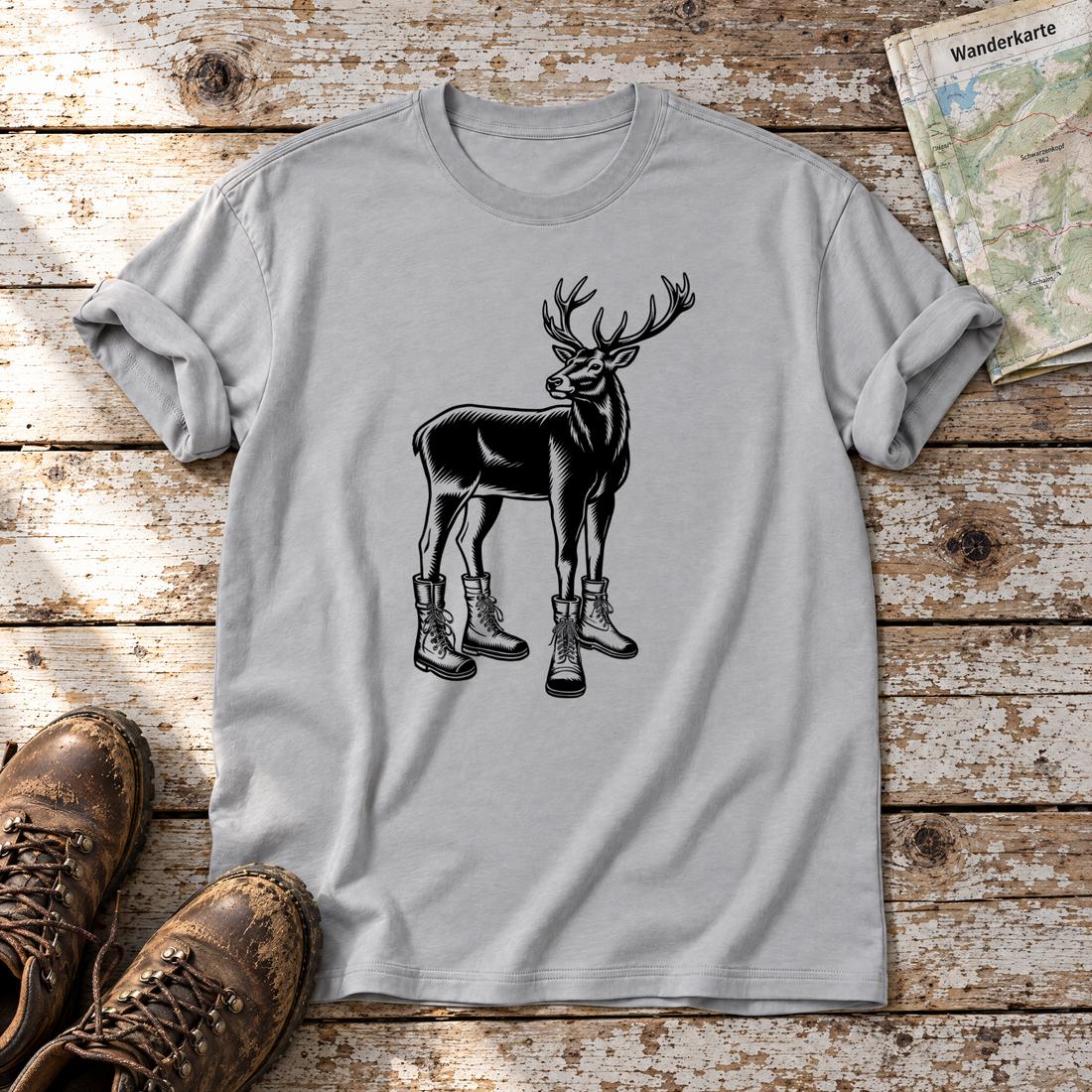 Hirsch in Bergschuhen – T-Shirt Unisex in Hellgrau, flach liegend auf alten Holzbrettern mit Wanderschuhen und Wanderkarte.