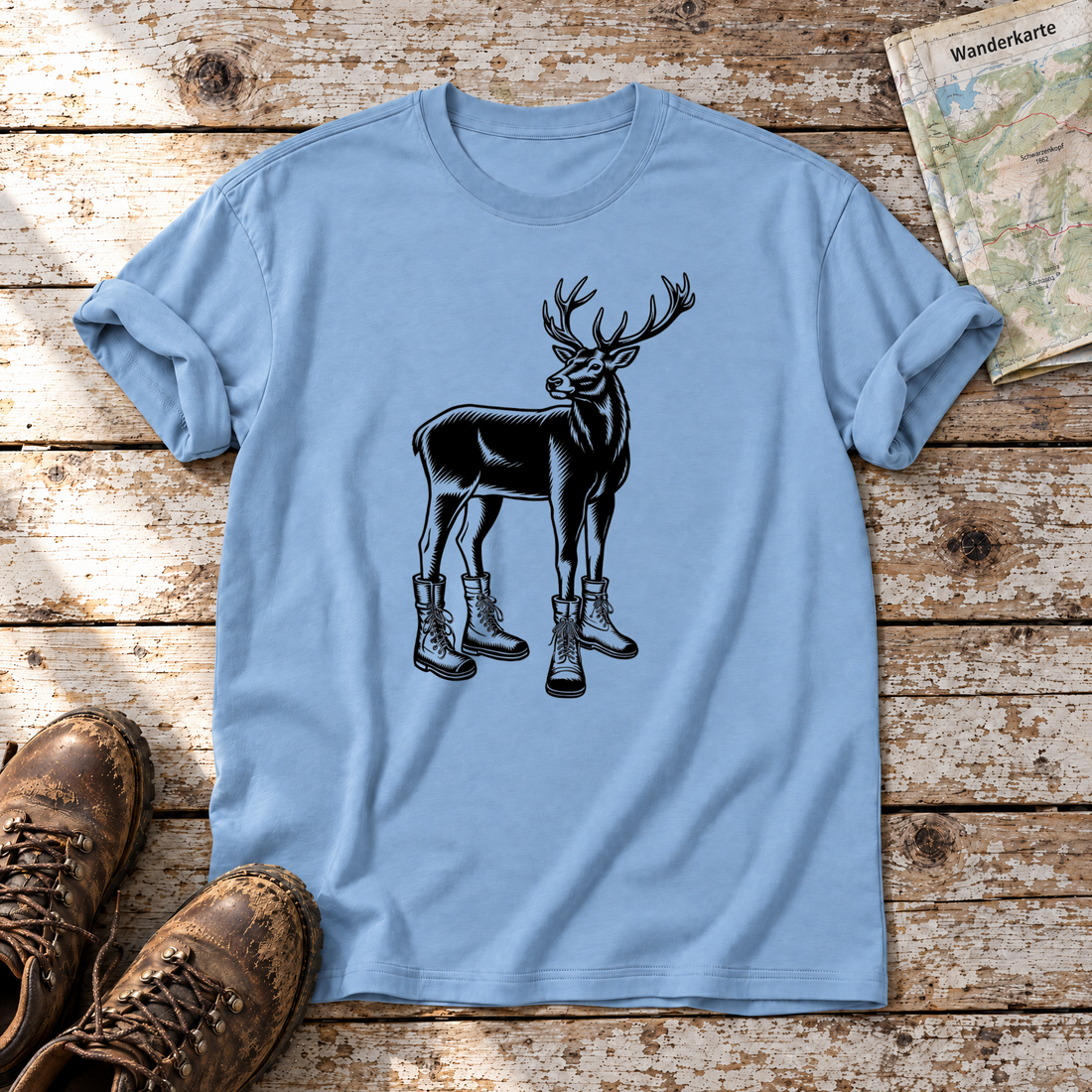 Hirsch in Bergschuhen – T-Shirt Unisex in Himmelblau, flach liegend auf alten Holzbrettern mit Wanderschuhen und Wanderkarte.