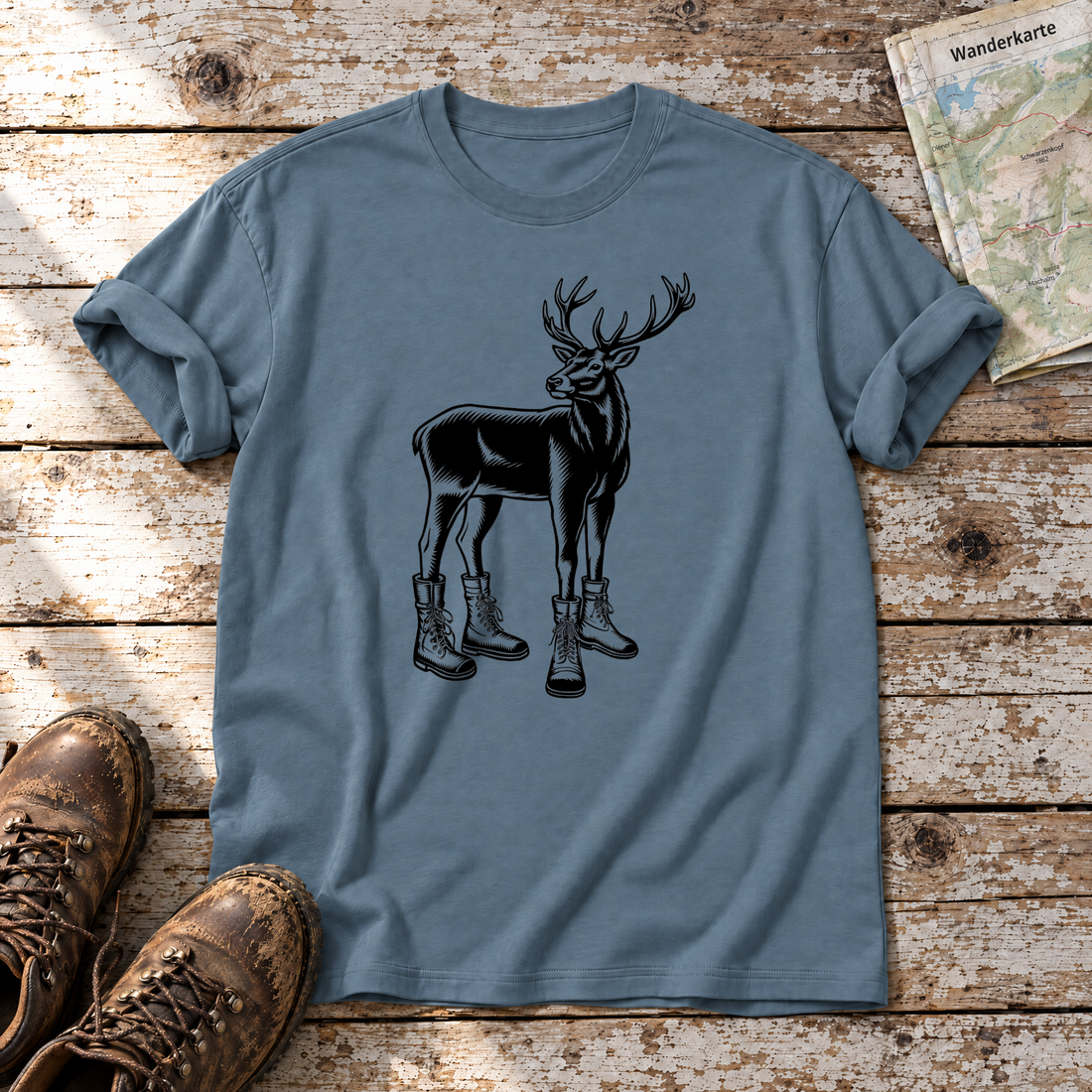 Hirsch in Bergschuhen – T-Shirt Unisex in Steinblau, flach liegend auf alten Holzbrettern mit Wanderschuhen und Wanderkarte.