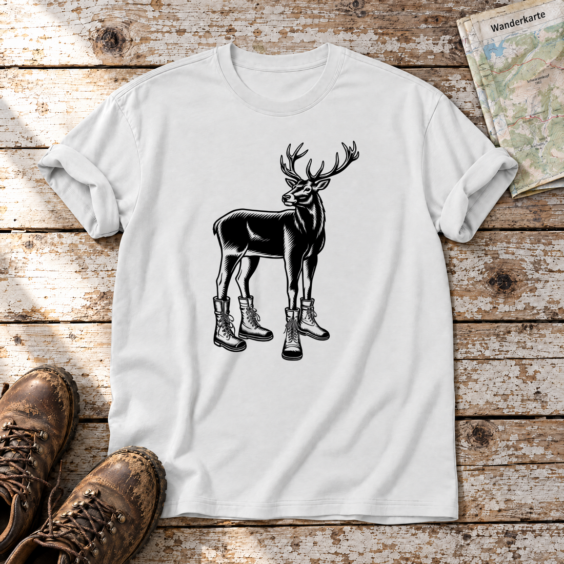 Hirsch in Bergschuhen – T-Shirt Unisex in Weiß, flach liegend auf alten Holzbrettern mit Wanderschuhen und Wanderkarte.