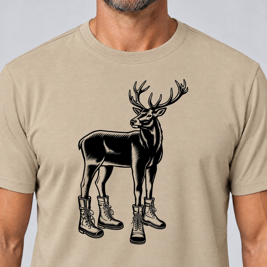 Nahaufnahme des Drucks: Hirsch in Bergschuhen – T-Shirt Unisex in Sand, von einem Mann getragen