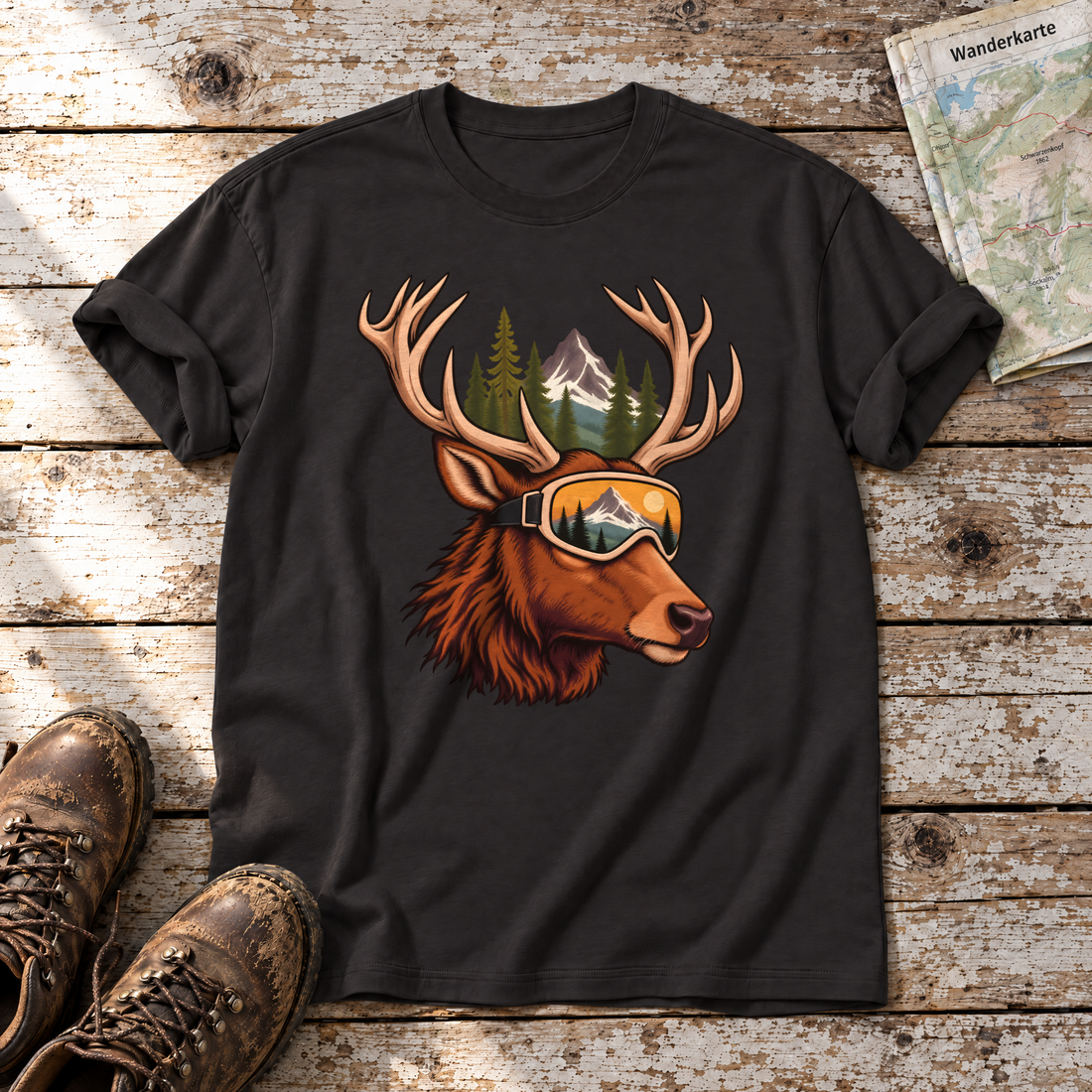 Hirsch mit Skibrille – T-Shirt Unisex in Schwarz, flach liegend auf alten Holzbrettern mit Wanderschuhen und Wanderkarte.