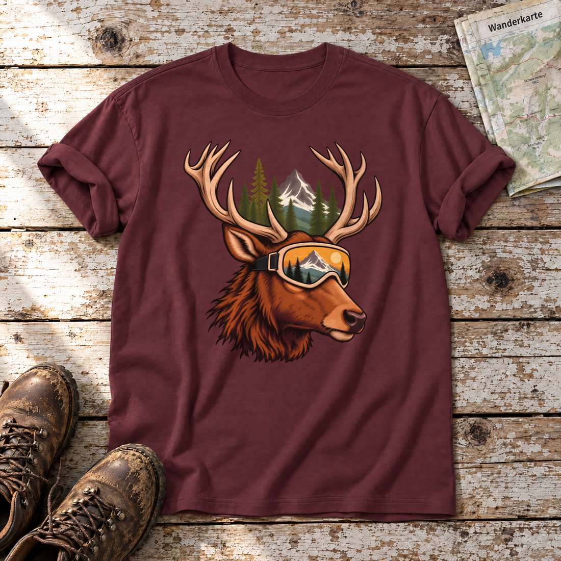 Hirsch mit Skibrille – T-Shirt Unisex in Bordeaux, flach liegend auf alten Holzbrettern mit Wanderschuhen und Wanderkarte.