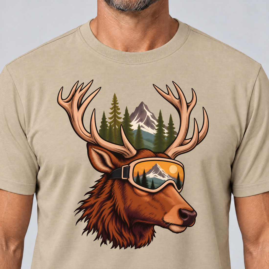 Nahaufnahme des Drucks: Hirsch mit Skibrille – T-Shirt Unisex in Sand, von einem Mann getragen