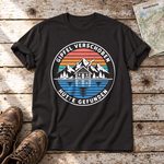 Gipfel verschoben, Hütte gefunden – T-Shirt Unisex in Schwarz, flach liegend auf alten Holzbrettern mit Wanderschuhen und Wanderkarte.