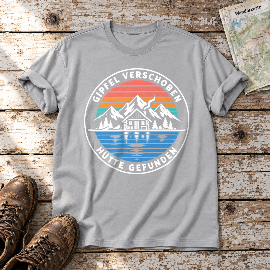 Gipfel verschoben, Hütte gefunden – T-Shirt Unisex in Hellgrau, flach liegend auf alten Holzbrettern mit Wanderschuhen und Wanderkarte.