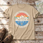 Gipfel verschoben, Hütte gefunden – T-Shirt Unisex in Sand, flach liegend auf alten Holzbrettern mit Wanderschuhen und Wanderkarte.
