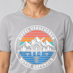 Nahaufnahme des Drucks: Gipfel verschoben, Hütte gefunden – T-Shirt Unisex in Hellgrau, von einer Frau getragen