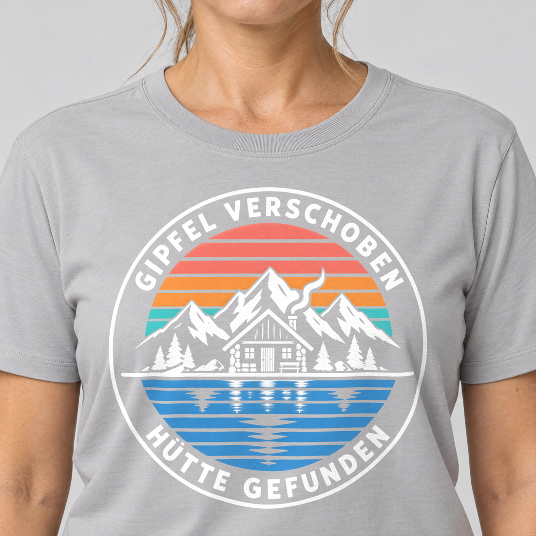 Nahaufnahme des Drucks: Gipfel verschoben, Hütte gefunden – T-Shirt Unisex in Hellgrau, von einer Frau getragen