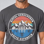 Nahaufnahme des Drucks: Gipfel verschoben, Hütte gefunden – T-Shirt Unisex in Dunkelgrau, von einem Mann getragen