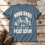 Hütte in Sicht, passt schon – T-Shirt Unisex in Steinblau, flach liegend auf alten Holzbrettern mit Wanderschuhen und Wanderkarte.