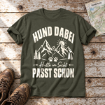 Hütte in Sicht, passt schon – T-Shirt Unisex in Oliv, flach liegend auf alten Holzbrettern mit Wanderschuhen und Wanderkarte.
