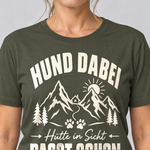 Nahaufnahme des Drucks: Hütte in Sicht, passt schon – T-Shirt Unisex in Oliv, von einer Frau getragen