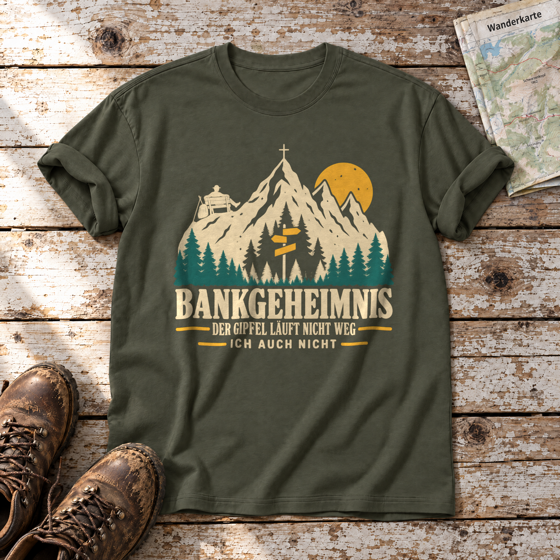 Bankgeheimnis – T-Shirt Unisex in Oliv, flach liegend auf alten Holzbrettern mit Wanderschuhen und Wanderkarte.