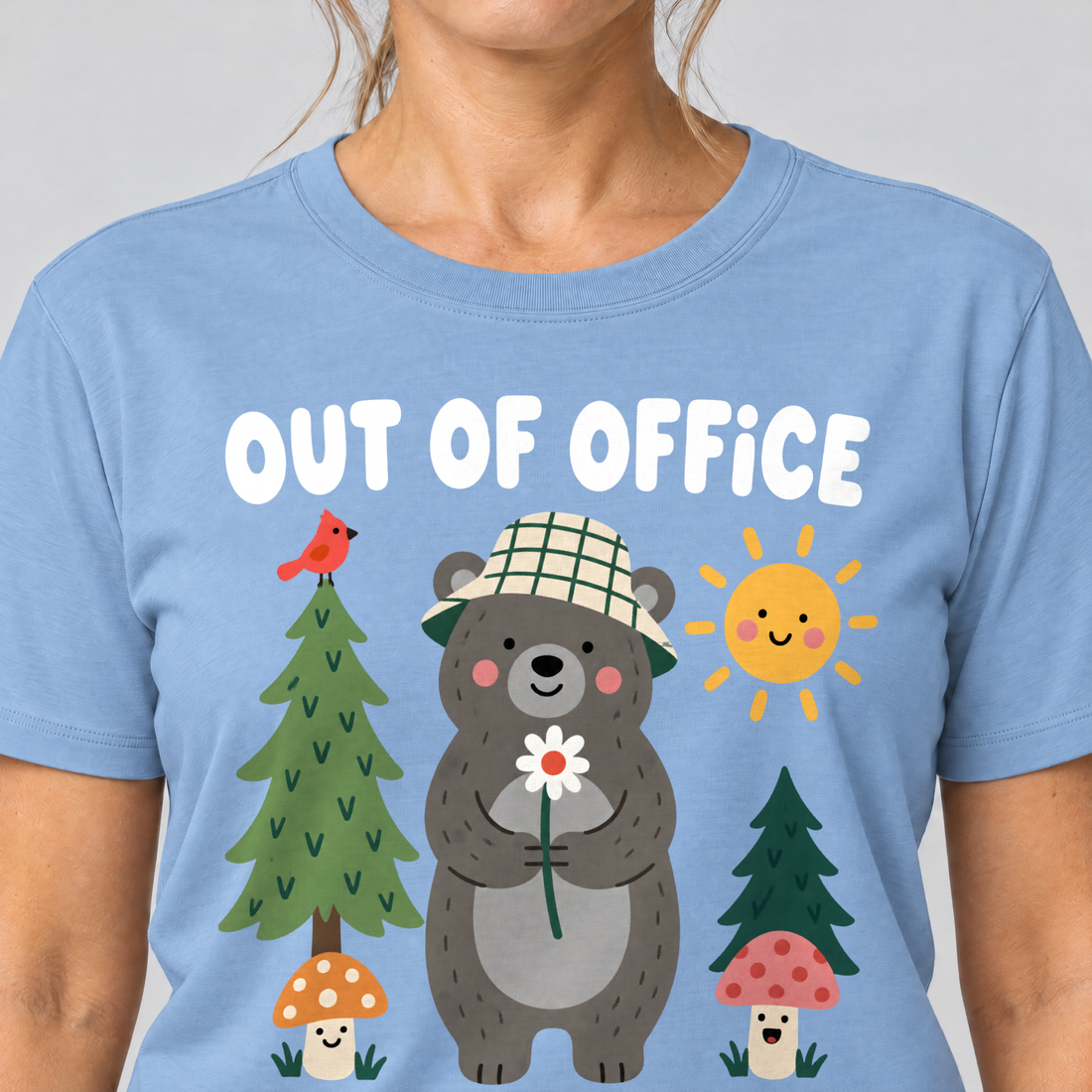 Nahaufnahme des Drucks: Out of Office – into the Woods – T-Shirt Unisex in Himmelblau, von einer Frau getragen