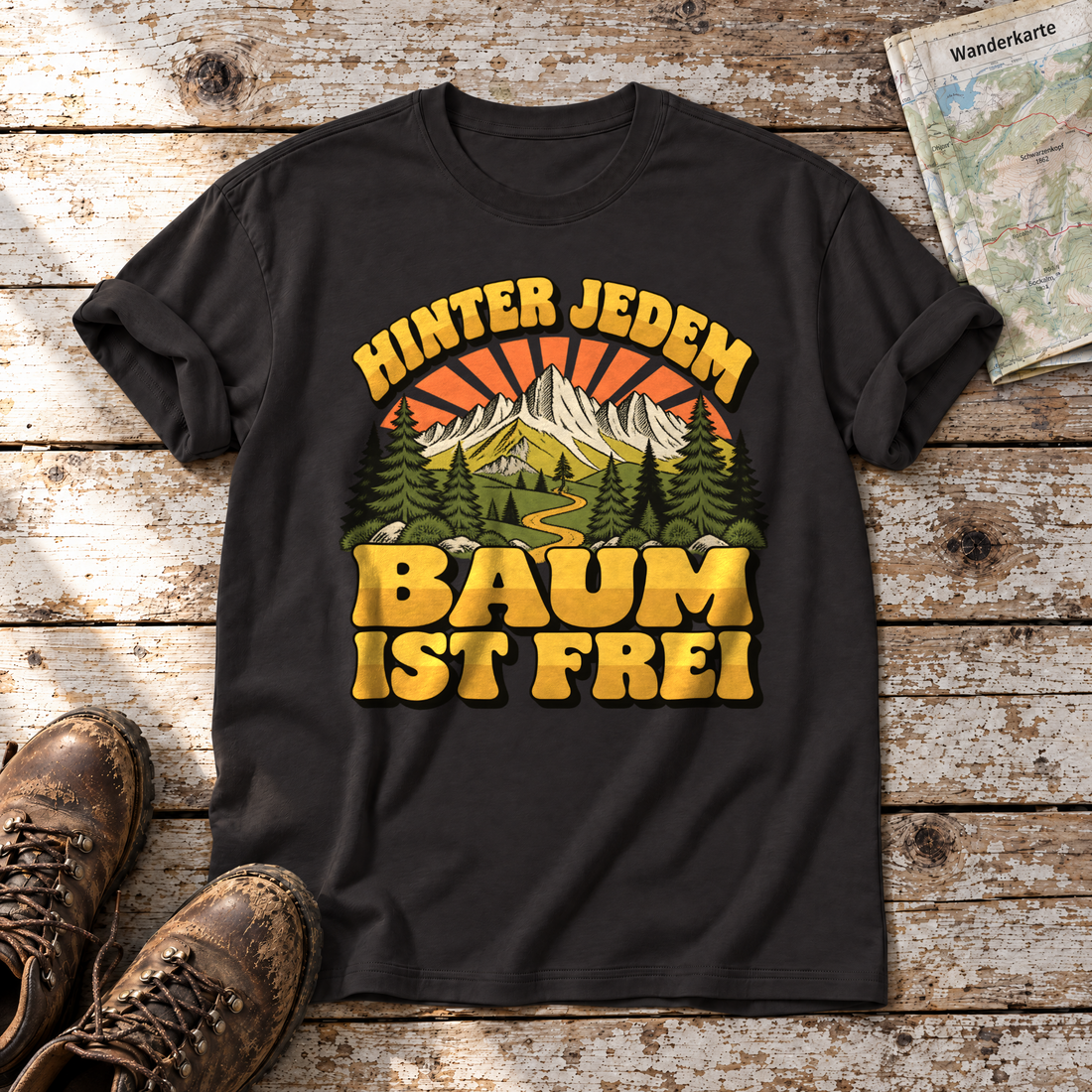 Hinter jedem Baum ist frei – T-Shirt Unisex in Schwarz, flach liegend auf alten Holzbrettern mit Wanderschuhen und Wanderkarte.