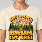 Nahaufnahme des Drucks: Hinter jedem Baum ist frei – T-Shirt Unisex in Natur, von einer Frau getragen