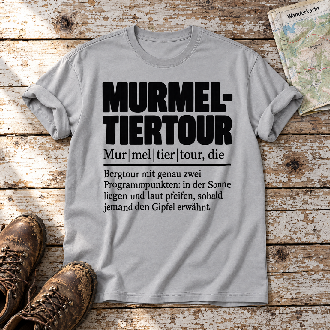 Murmeltiertour – T-Shirt Unisex in Hellgrau, flach liegend auf alten Holzbrettern mit Wanderschuhen und Wanderkarte.