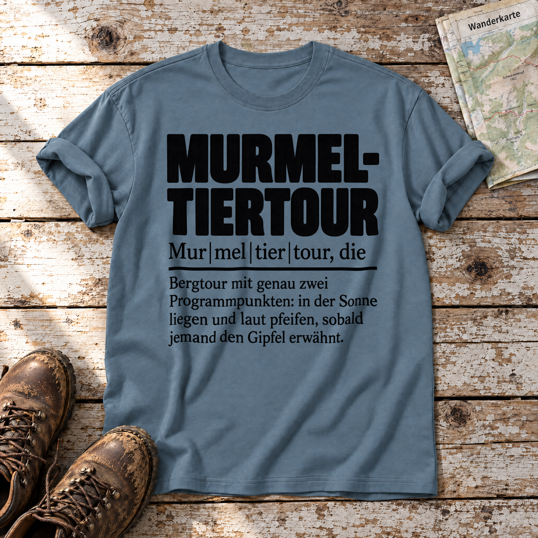 Murmeltiertour – T-Shirt Unisex in Steinblau, flach liegend auf alten Holzbrettern mit Wanderschuhen und Wanderkarte.