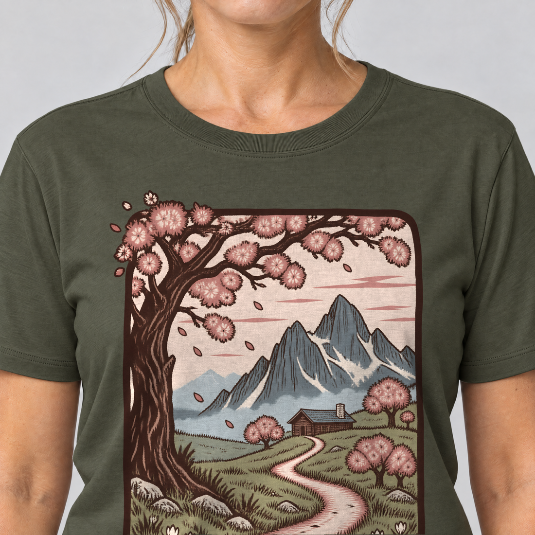 Nahaufnahme des Drucks: Almweg zur Hütte – T-Shirt Unisex in Oliv, von einer Frau getragen