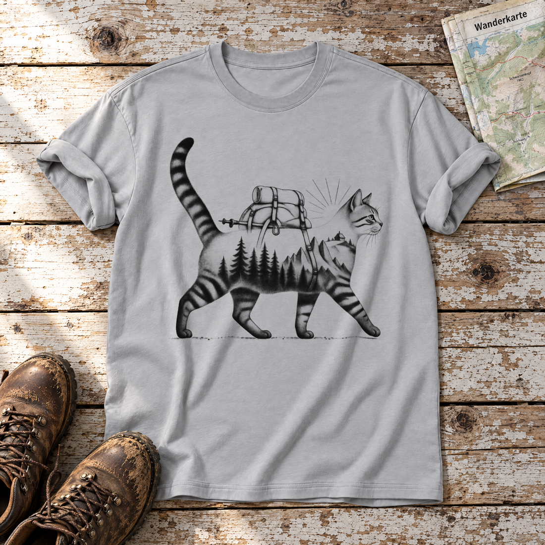 Katze mit Rucksack – T-Shirt Unisex in Hellgrau, flach liegend auf alten Holzbrettern mit Wanderschuhen und Wanderkarte.