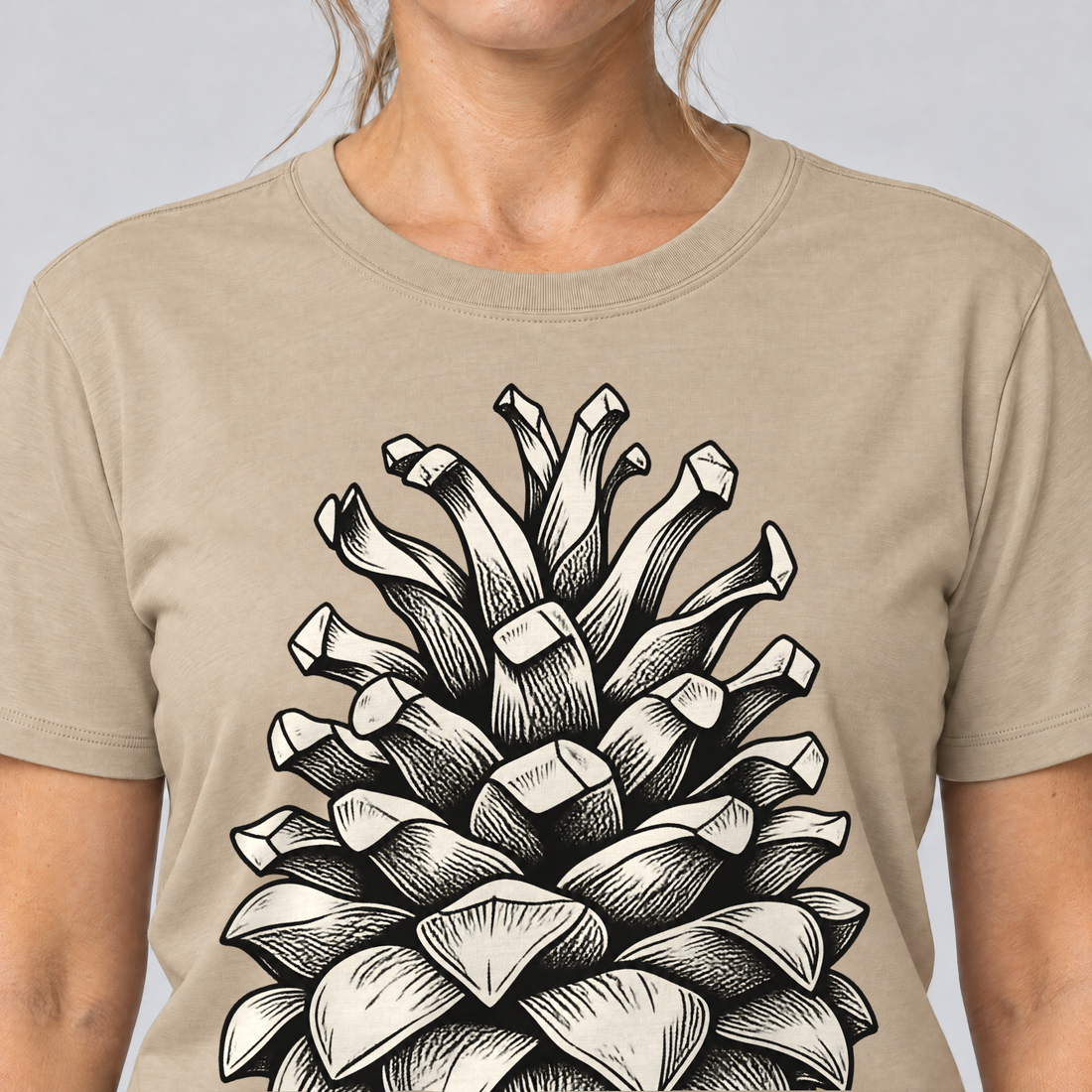Nahaufnahme des Drucks: Kiefernzapfen – T-Shirt Unisex in Sand, von einer Frau getragen