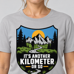 Nahaufnahme des Drucks: Another Kilometer or So – T-Shirt Unisex in Hellgrau, von einer Frau getragen