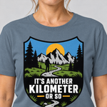 Nahaufnahme des Drucks: Another Kilometer or So – T-Shirt Unisex in Steinblau, von einer Frau getragen