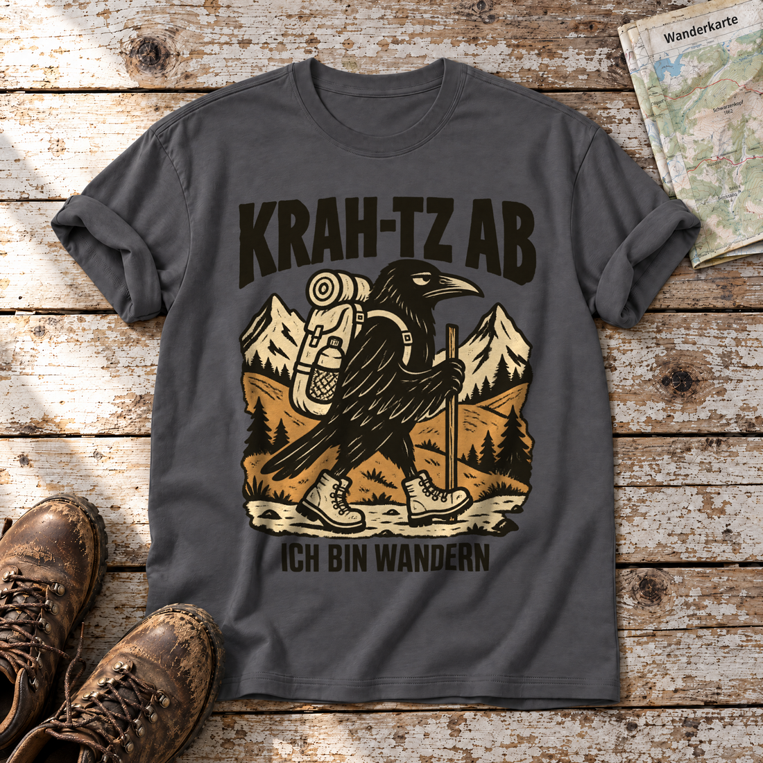 Krah-tz ab – T-Shirt Unisex in Dunkelgrau, flach liegend auf alten Holzbrettern mit Wanderschuhen und Wanderkarte.