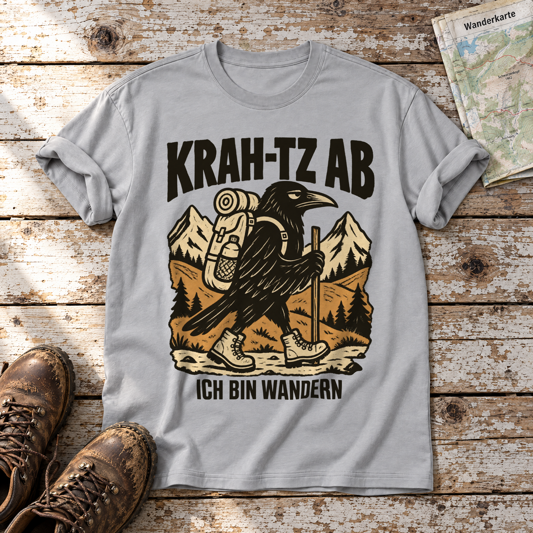 Krah-tz ab – T-Shirt Unisex in Hellgrau, flach liegend auf alten Holzbrettern mit Wanderschuhen und Wanderkarte.