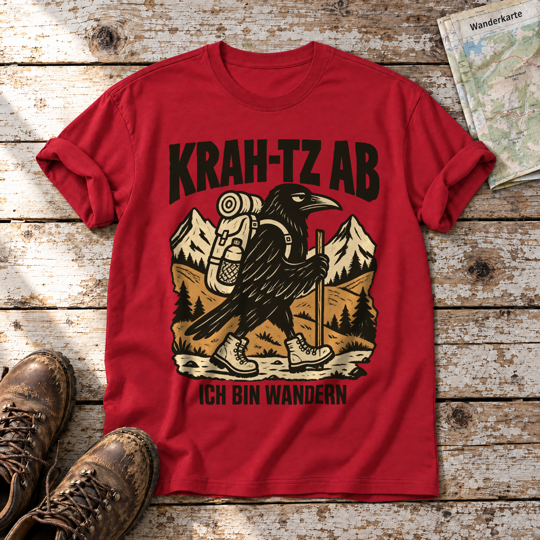 Krah-tz ab – T-Shirt Unisex in Rot, flach liegend auf alten Holzbrettern mit Wanderschuhen und Wanderkarte.