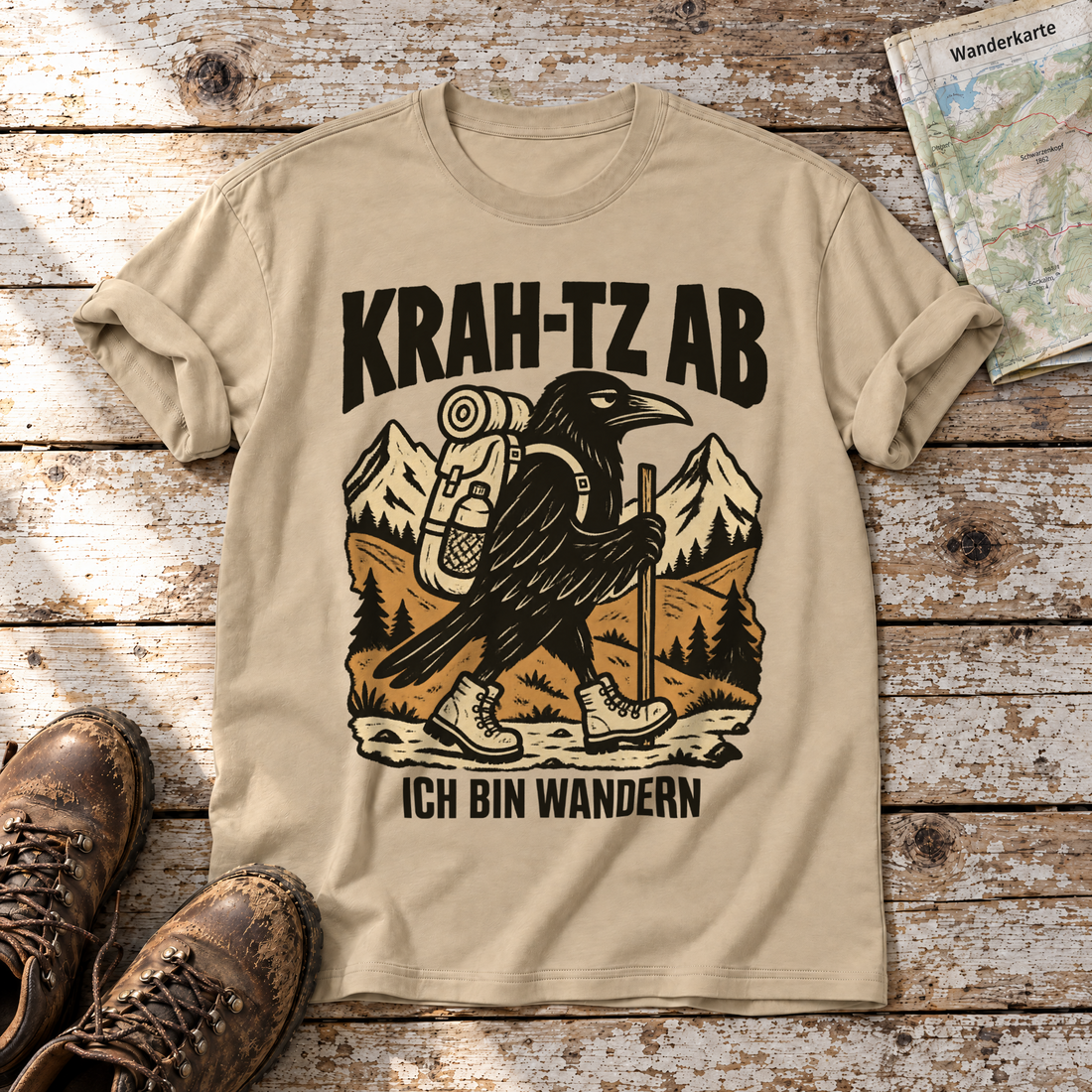 Krah-tz ab – T-Shirt Unisex in Sand, flach liegend auf alten Holzbrettern mit Wanderschuhen und Wanderkarte.