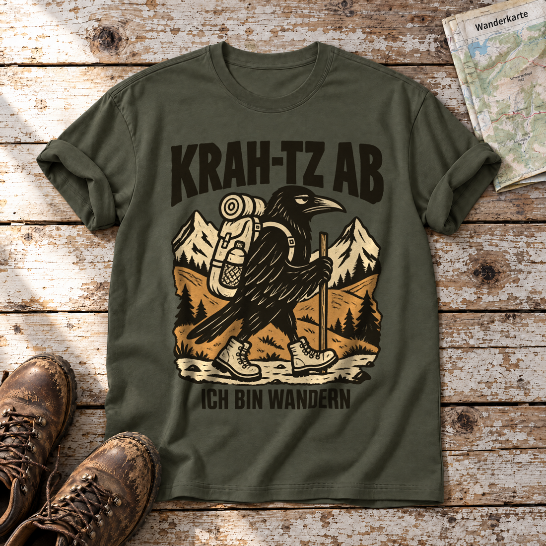 Krah-tz ab – T-Shirt Unisex in Oliv, flach liegend auf alten Holzbrettern mit Wanderschuhen und Wanderkarte.