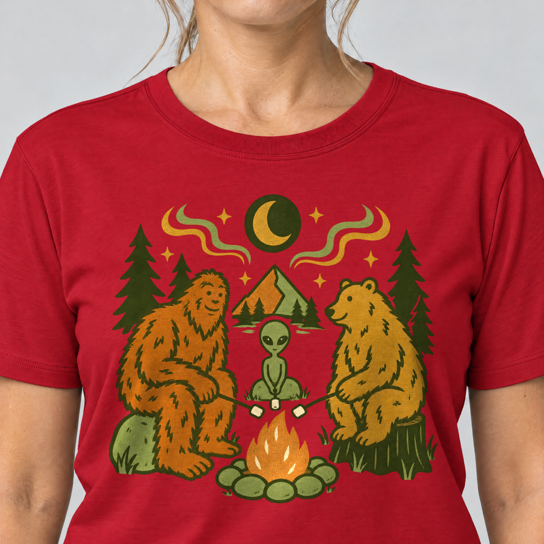Nahaufnahme des Drucks: Bigfoot, Alien und Bär am Lagerfeuer – T-Shirt Unisex in Rot, von einer Frau getragen