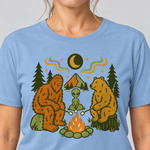 Nahaufnahme des Drucks: Bigfoot, Alien und Bär am Lagerfeuer – T-Shirt Unisex in Himmelblau, von einer Frau getragen