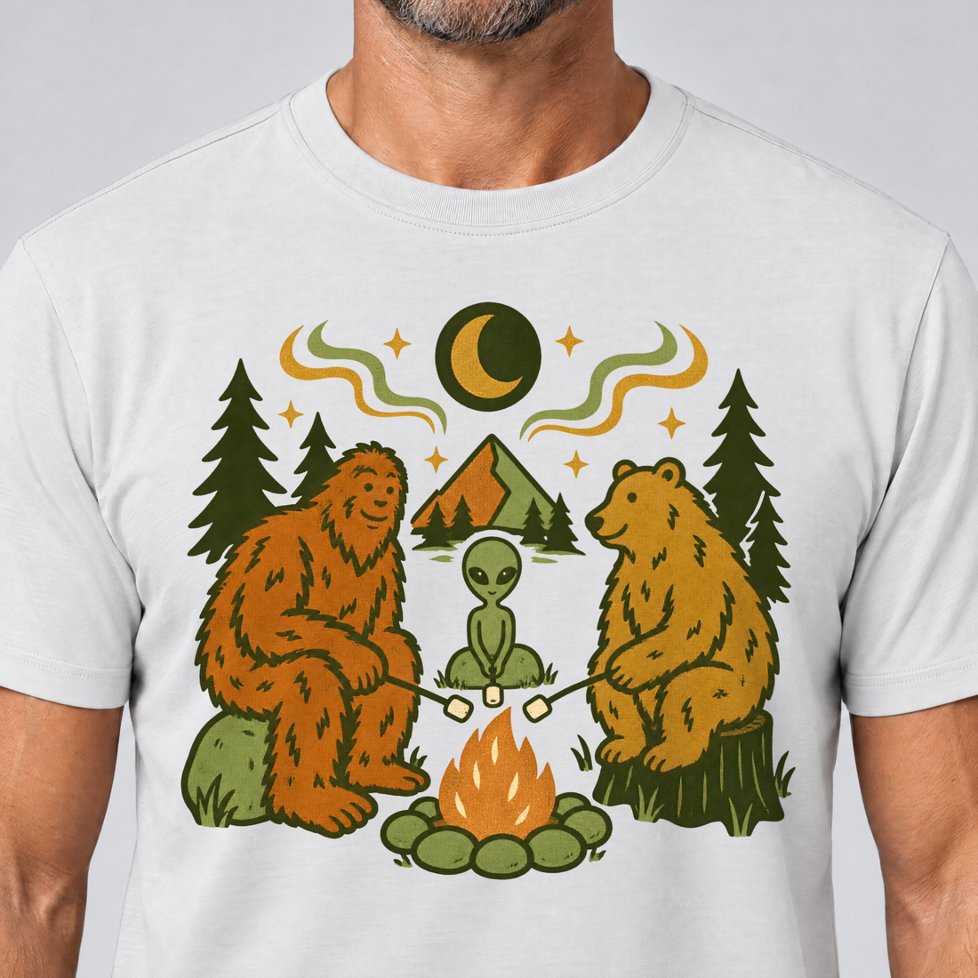 Nahaufnahme des Drucks: Bigfoot, Alien und Bär am Lagerfeuer – T-Shirt Unisex in Weiß, von einem Mann getragen