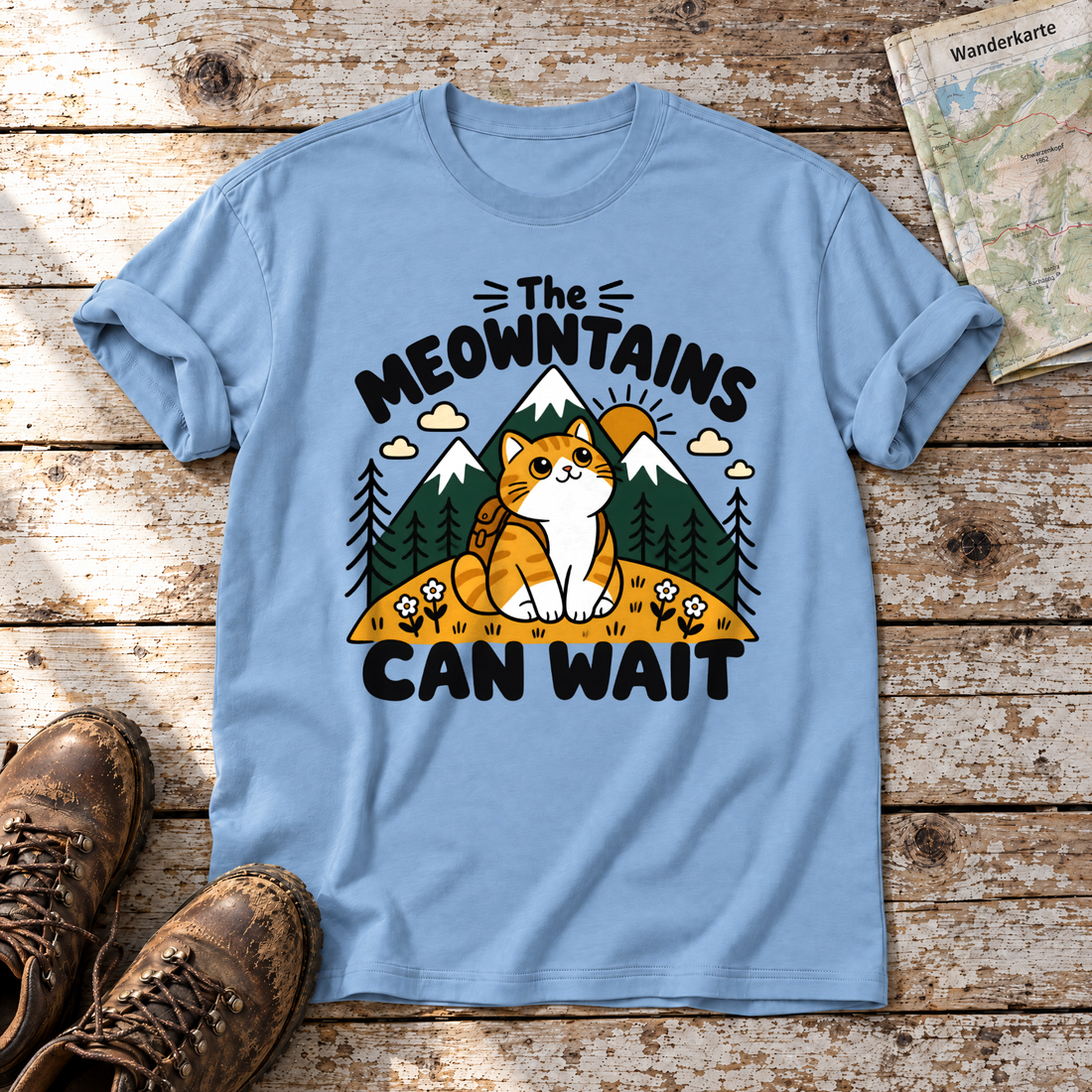 The Meowntains can wait – T-Shirt Unisex in Himmelblau, flach liegend auf alten Holzbrettern mit Wanderschuhen und Wanderkarte.
