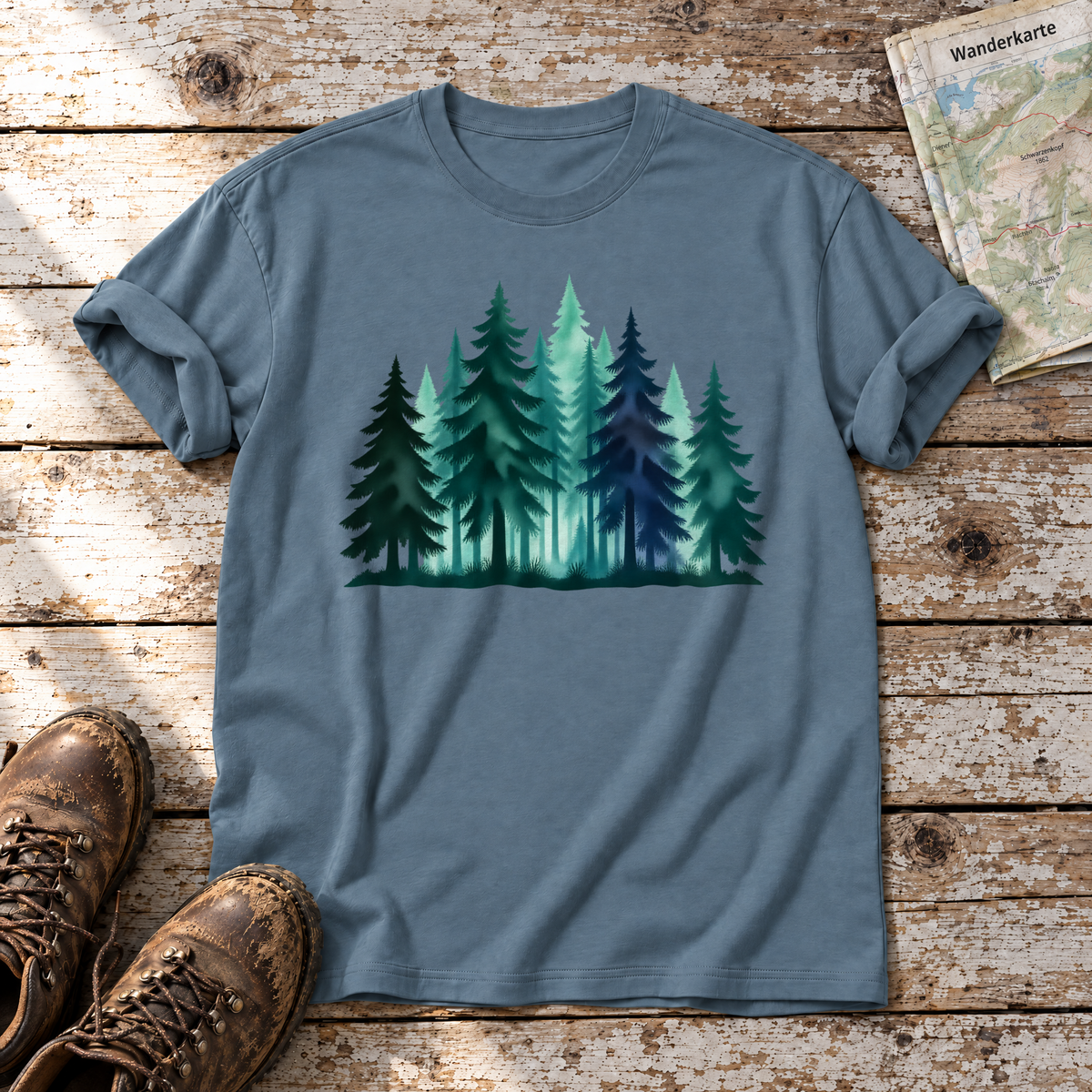 Nebelwald – T-Shirt Unisex in Steinblau, flach liegend auf alten Holzbrettern mit Wanderschuhen und Wanderkarte.