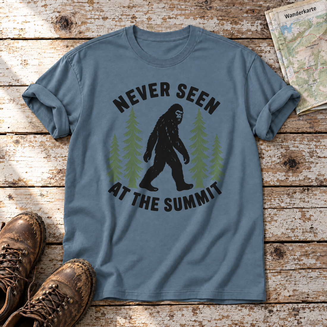 Never seen at the summit – T-Shirt Unisex in Steinblau, flach liegend auf alten Holzbrettern mit Wanderschuhen und Wanderkarte.