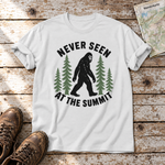 Never seen at the summit – T-Shirt Unisex in Weiß, flach liegend auf alten Holzbrettern mit Wanderschuhen und Wanderkarte.